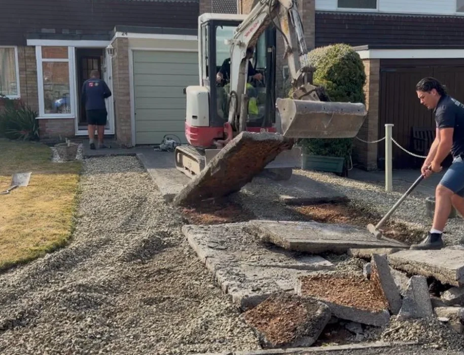 Mini excavator and groundworker breaking out an old concrete driveway before block paving installation in Trowbridge
