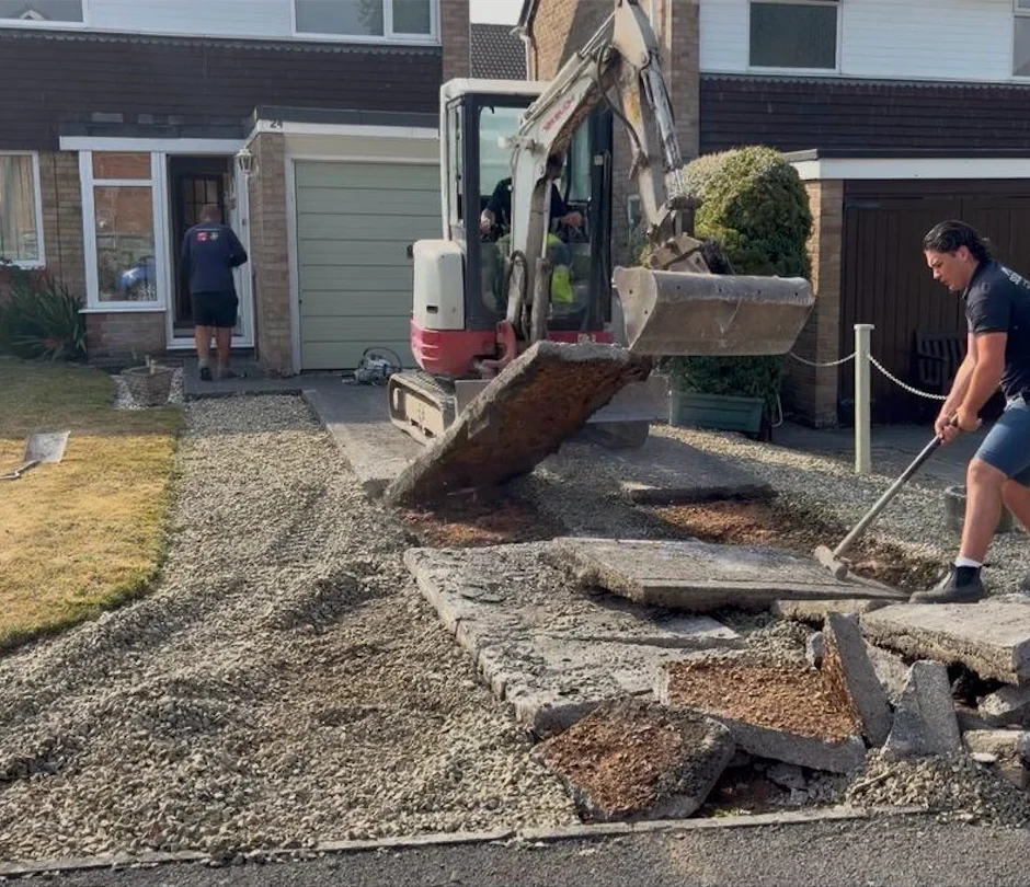 Mini excavator and groundworker breaking out an old concrete driveway before block paving installation in Trowbridge