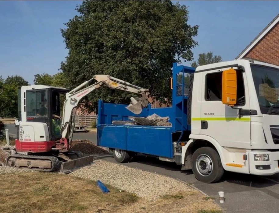 Excavator loading broken concrete and rubble into a muck-away truck during driveway excavation in Trowbridge