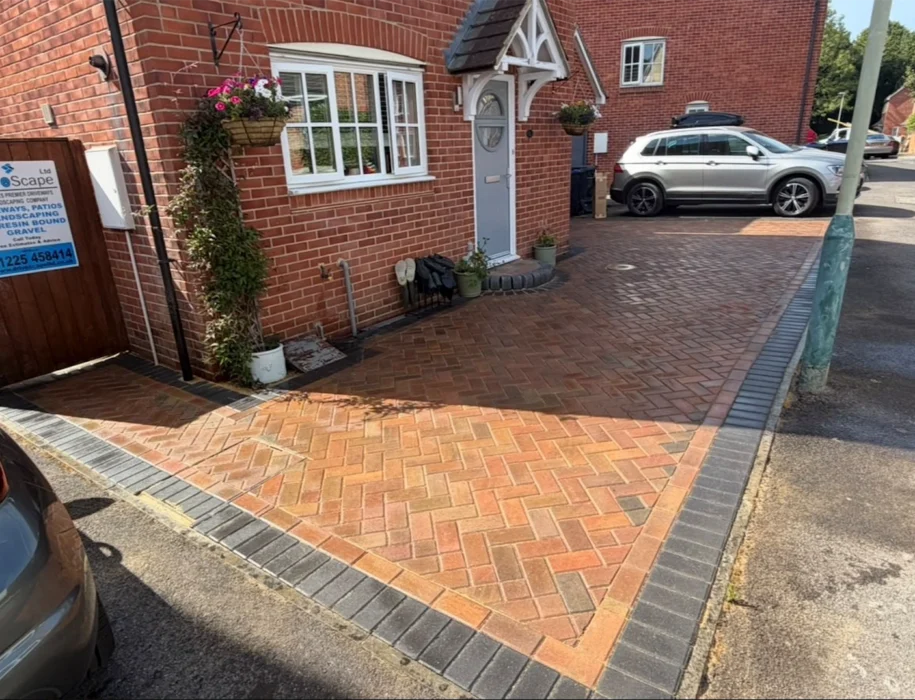 Herringbone block paving driveway with charcoal border and feature diamond panel outside a red-brick home in Wiltshire