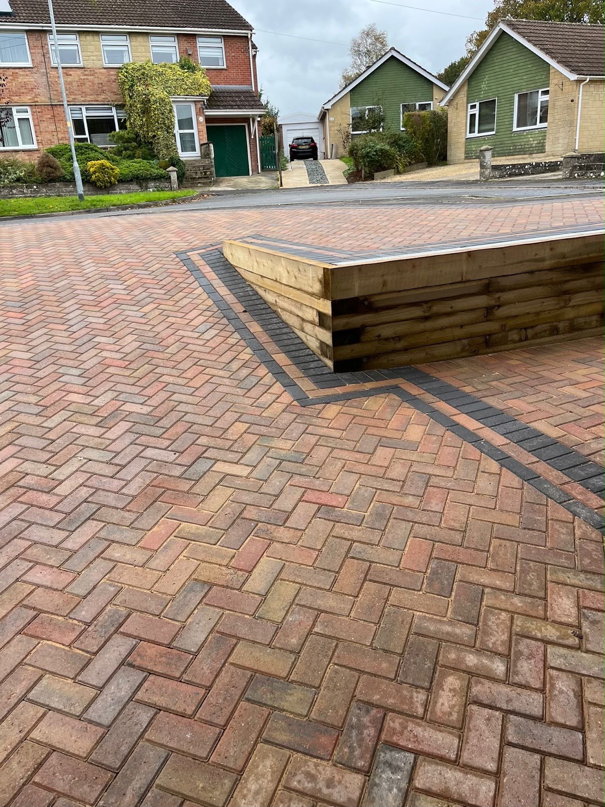 Herringbone block paving driveway with charcoal border and timber sleeper retaining wall in a Wiltshire cul-de-sac
